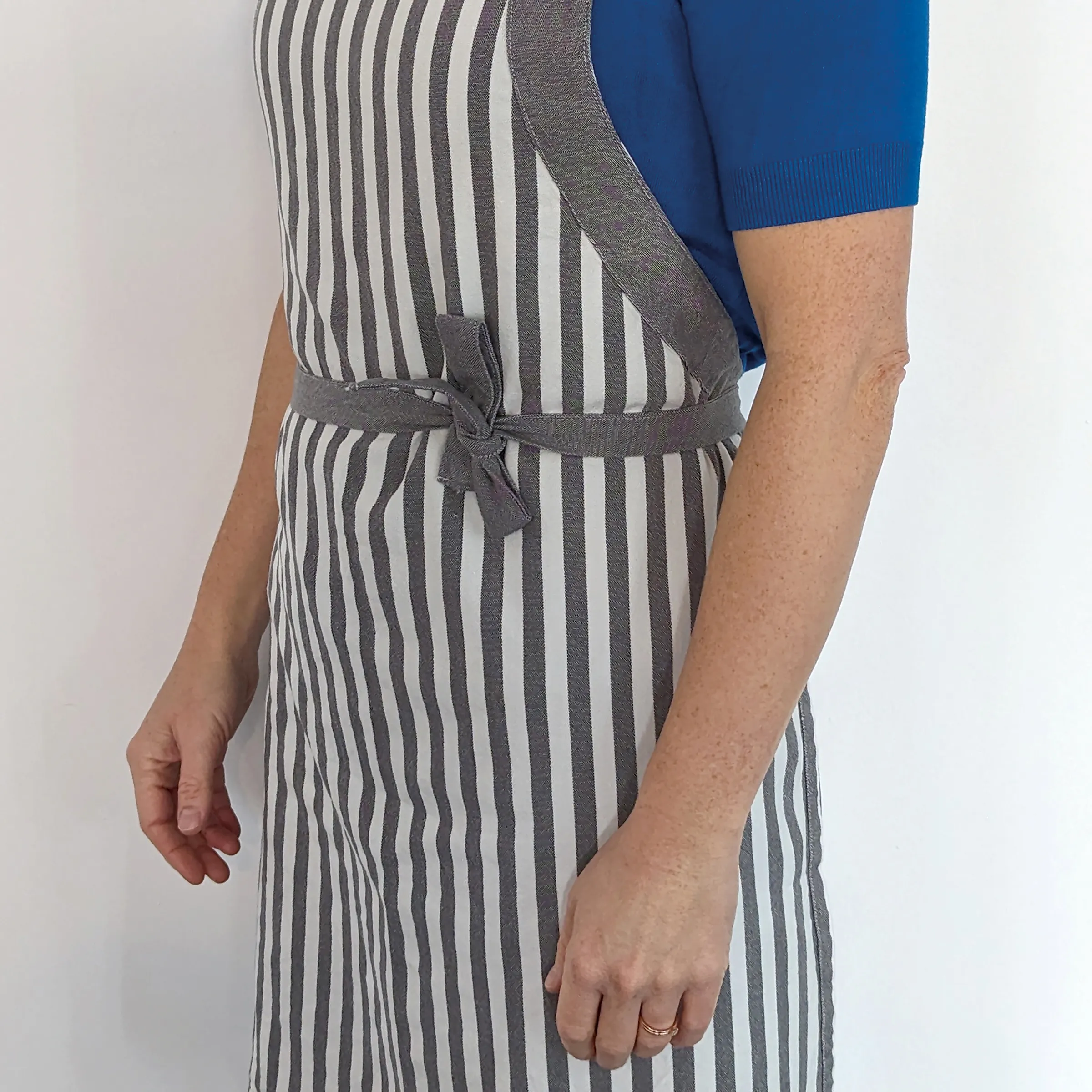 Leinenkleid gestreift mit Bindegürtel - Herrenmodetrend Mann trägt gestreiftes Leinenkleid in Grau-Weiß mit grauem Bindegürtel und blauem Cardigan