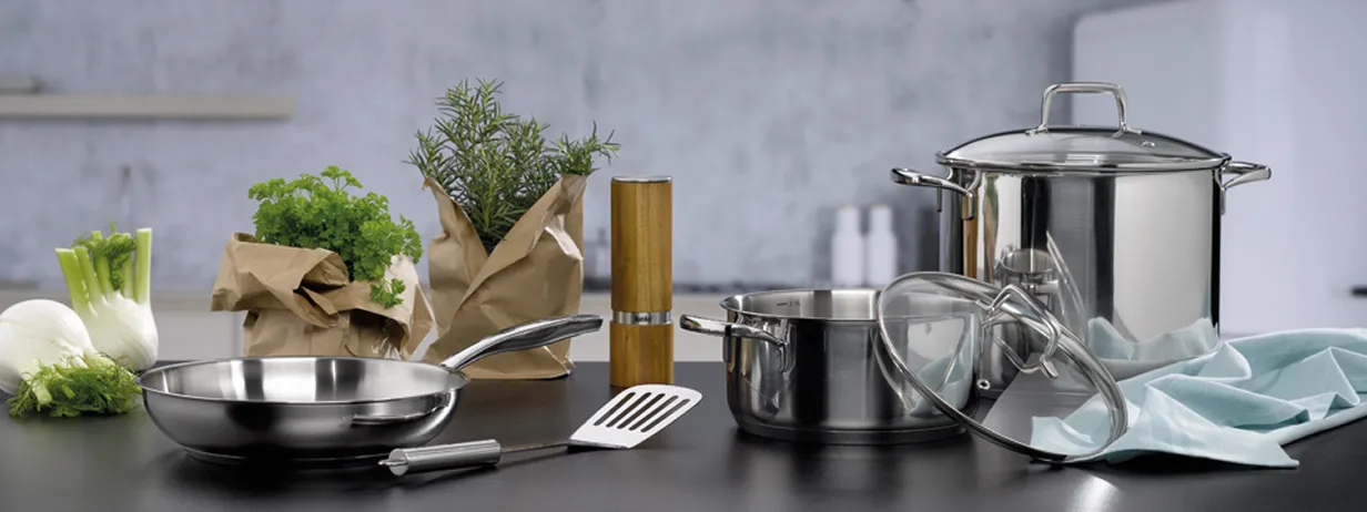 Edelstahl Kochgeschirr Set mit Töpfen und Pfanne für die moderne Küche Kochgeschirr-Set aus Edelstahl mit Töpfen, Pfanne und Küchenutensilien auf moderner Arbeitsplatte