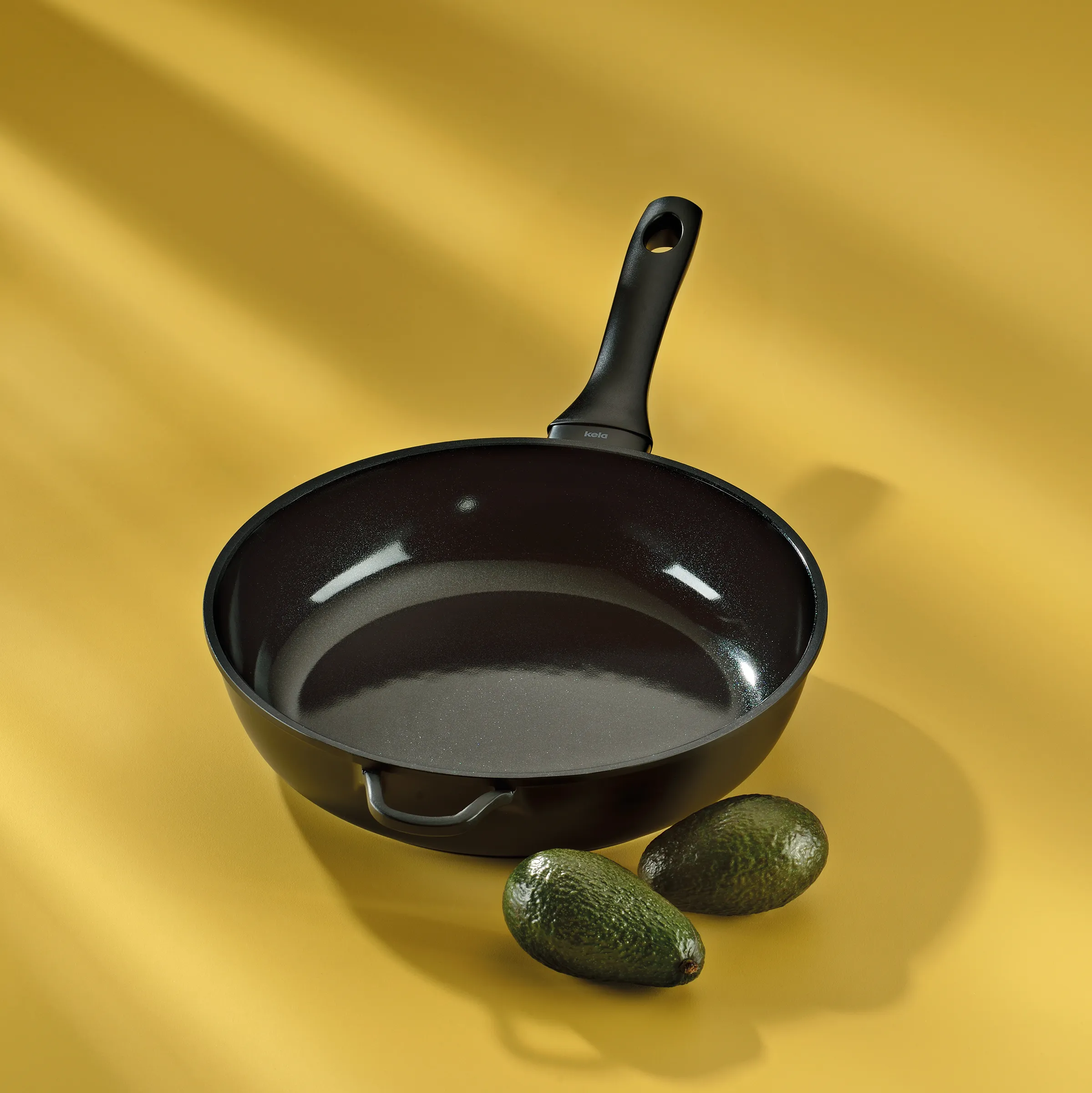 Antihaft-Bratpfanne schwarz mit Avocados – Kochgeschirr für die Küche Schwarze Bratpfanne mit ergonomischem Griff und zwei Avocados auf gelbem Hintergrund
