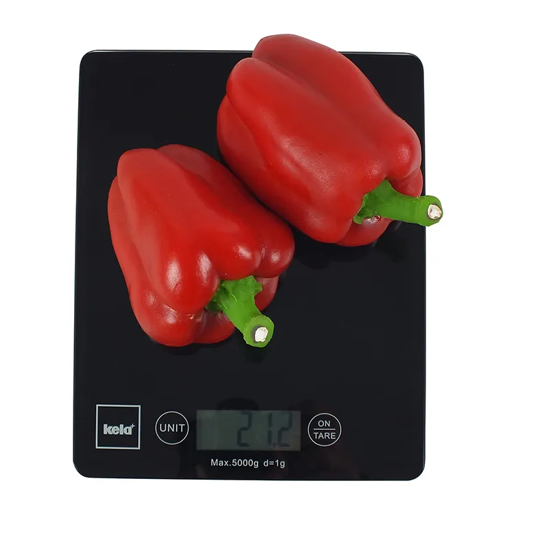 Rote Paprika auf digitaler Küchenwaage - Frisches Gemüse wiegen Zwei rote Paprika auf einer digitalen Küchenwaage mit Display, das 272 Gramm anzeigt