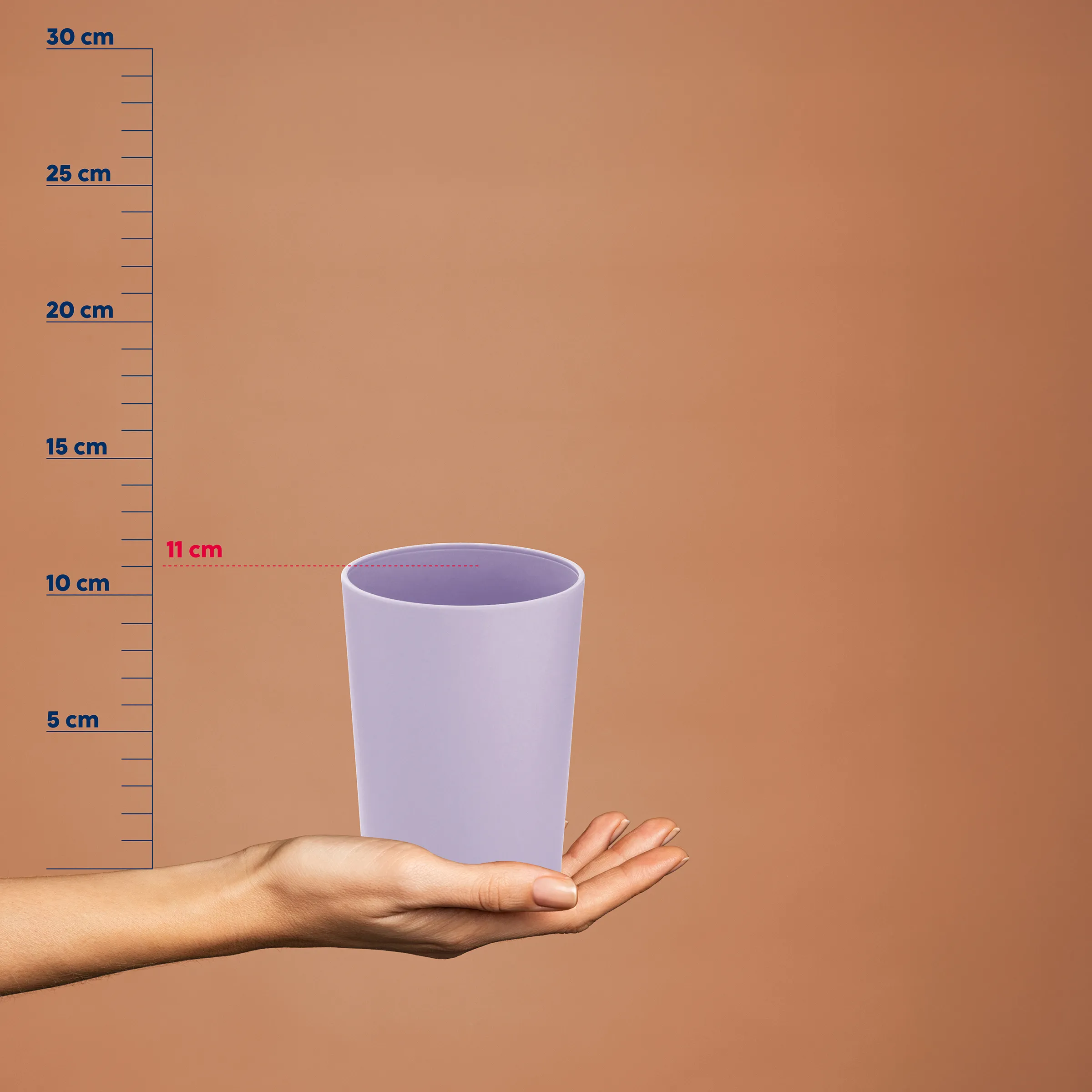 Lila Kunststoffbecher auf einer Hand mit Größenvergleichsskala von 5 bis 30 cm, zeigt Becher ca. 11 cm Höhe