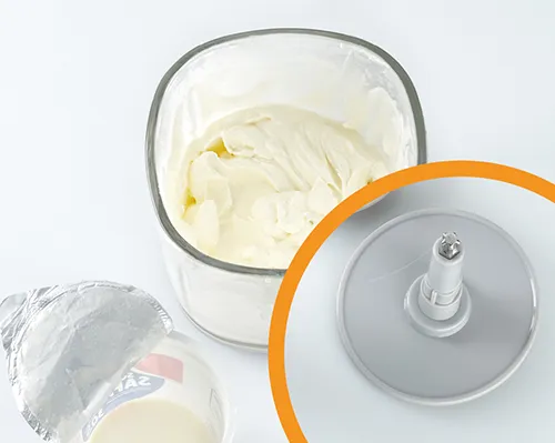 Butter-Rührmaschine für cremige Teige und Massen Küchenmaschine mit Rührschüssel gefüllt mit cremiger Butter-Masse, orangefarbener Deckel sichtbar