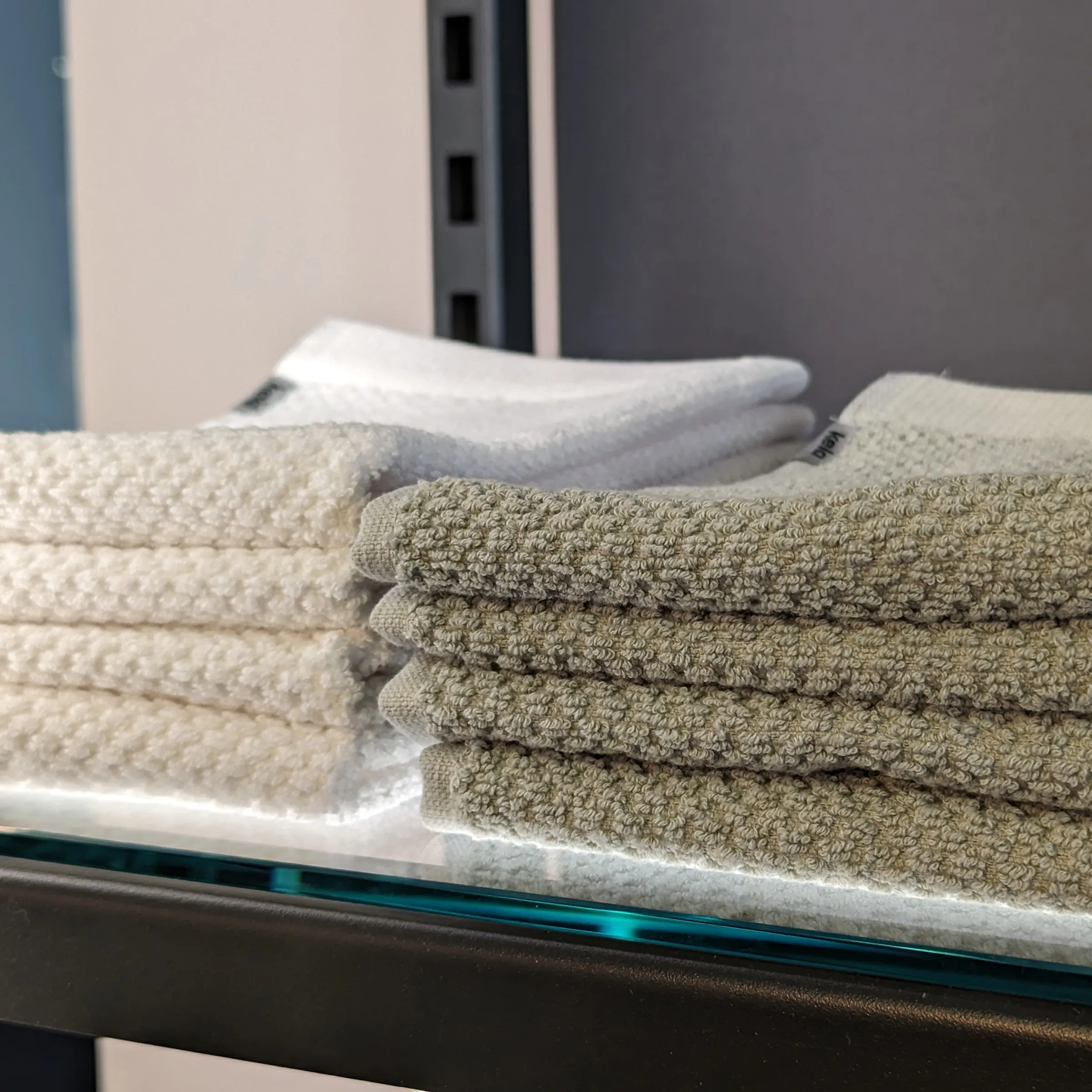 Handtücher Set beige weiß Bad - weiche Frottierhandtücher gefaltet Gestapelte beige und weiße Handtücher auf Glasablage im modernen Badezimmer
