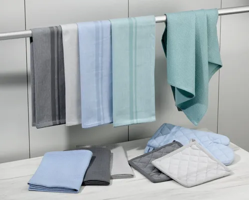 Handtücher Set - Badezimmer Textilien Collection Badezimmer-Set mit farbigen Handtüchern auf einer Stange und gefalteten Handtüchern sowie Badematte auf Tisch