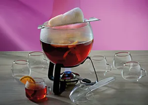 Schokoladenfondue Set mit Glasschmelztopf und Stövchen - Fondue Geschirr Fondue-Set mit dunkler Schokolade im Glasschmelztopf auf Stövchen, umgeben von leeren Gläsern