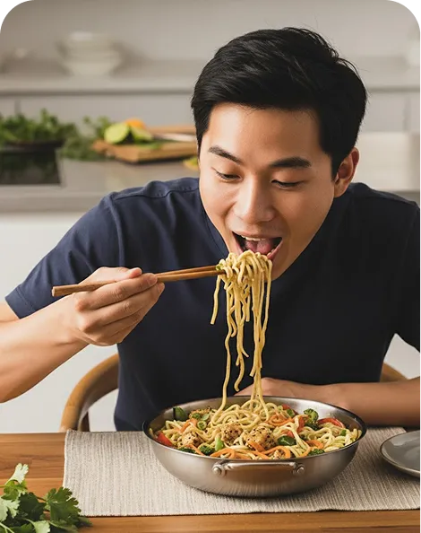 Noodle Soup - Man Enjoying Delicious Ramen Dish Young man eating delicious noodle soup with chopsticks from a bowl in a modern kitchen