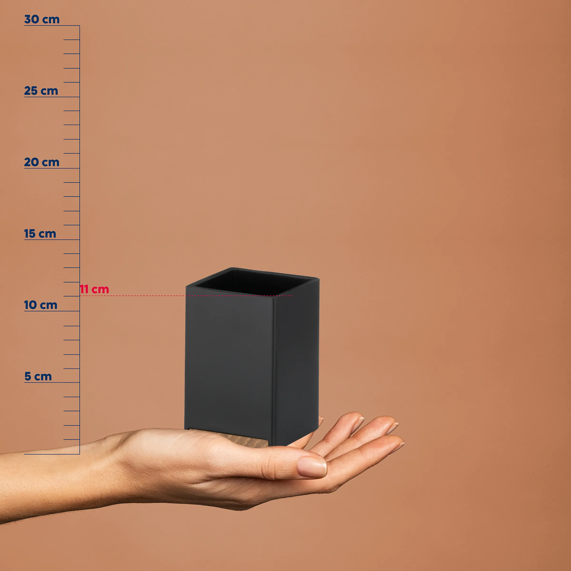 Schwarzer rechteckiger Behälter mit 11 cm Höhe liegt in einer Hand, neben einer Messskala bis 30 cm