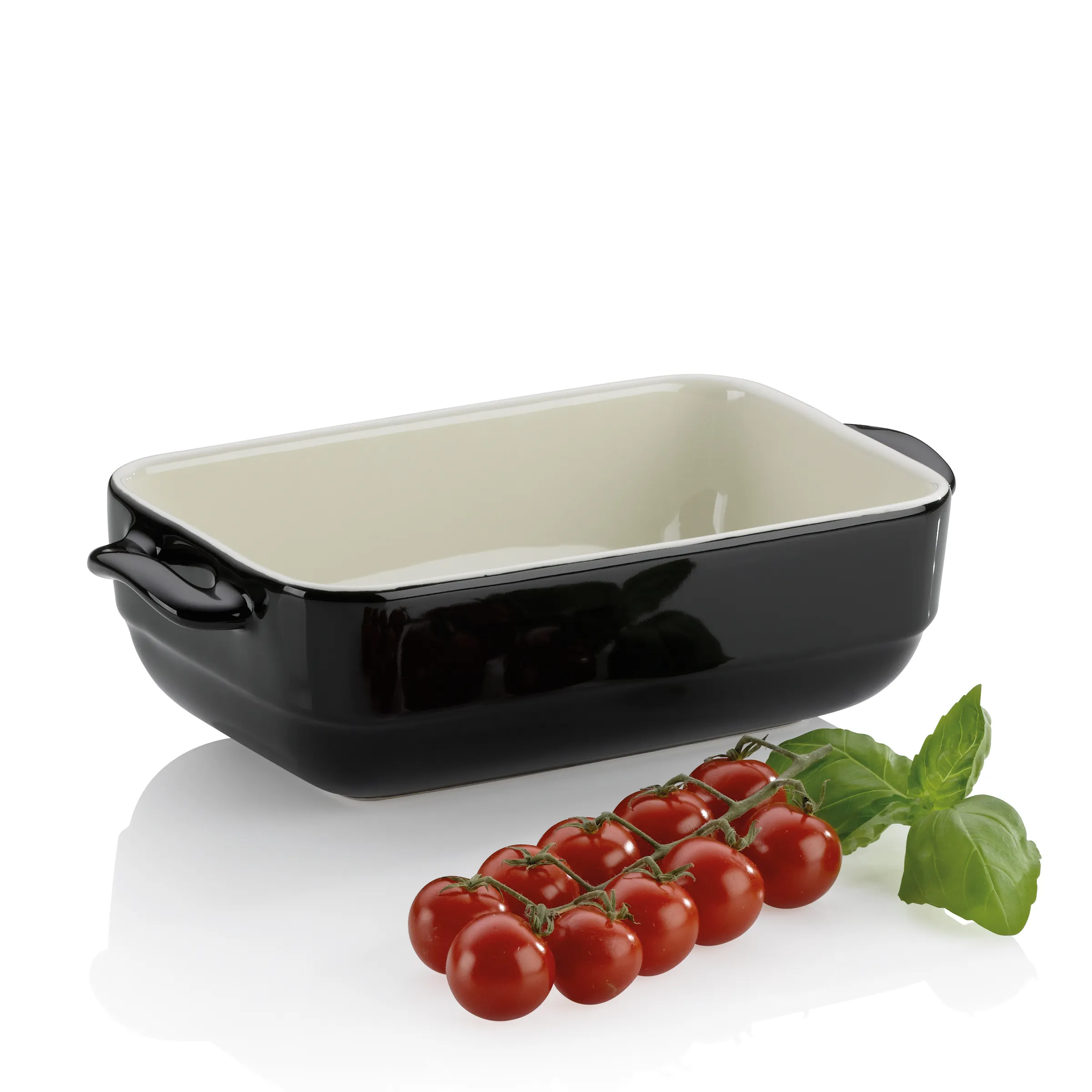 Keramik Backform schwarz - Ofenform für Kochen und Backen Schwarze Keramik-Backform mit cremefarbenem Inneren und Griffen, daneben frische Rispentomaten mit Basilikumblättern