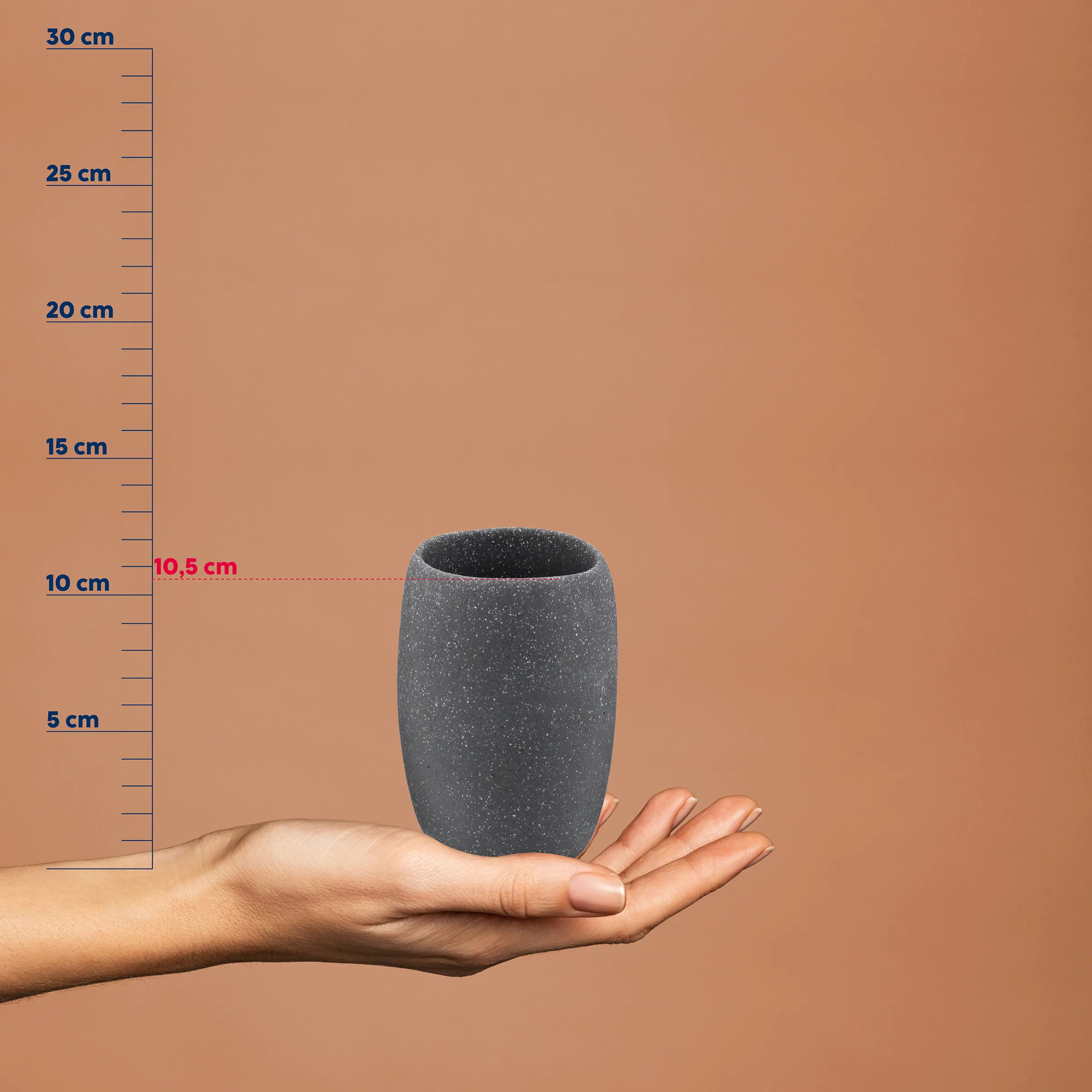 Graue Betonvase mit Körnung in einer Hand, daneben eine Messskala von 0 bis 30 cm