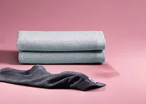Stapel grauer Handtücher und dunkles gefaltetes Handtuch auf rosa Hintergrund