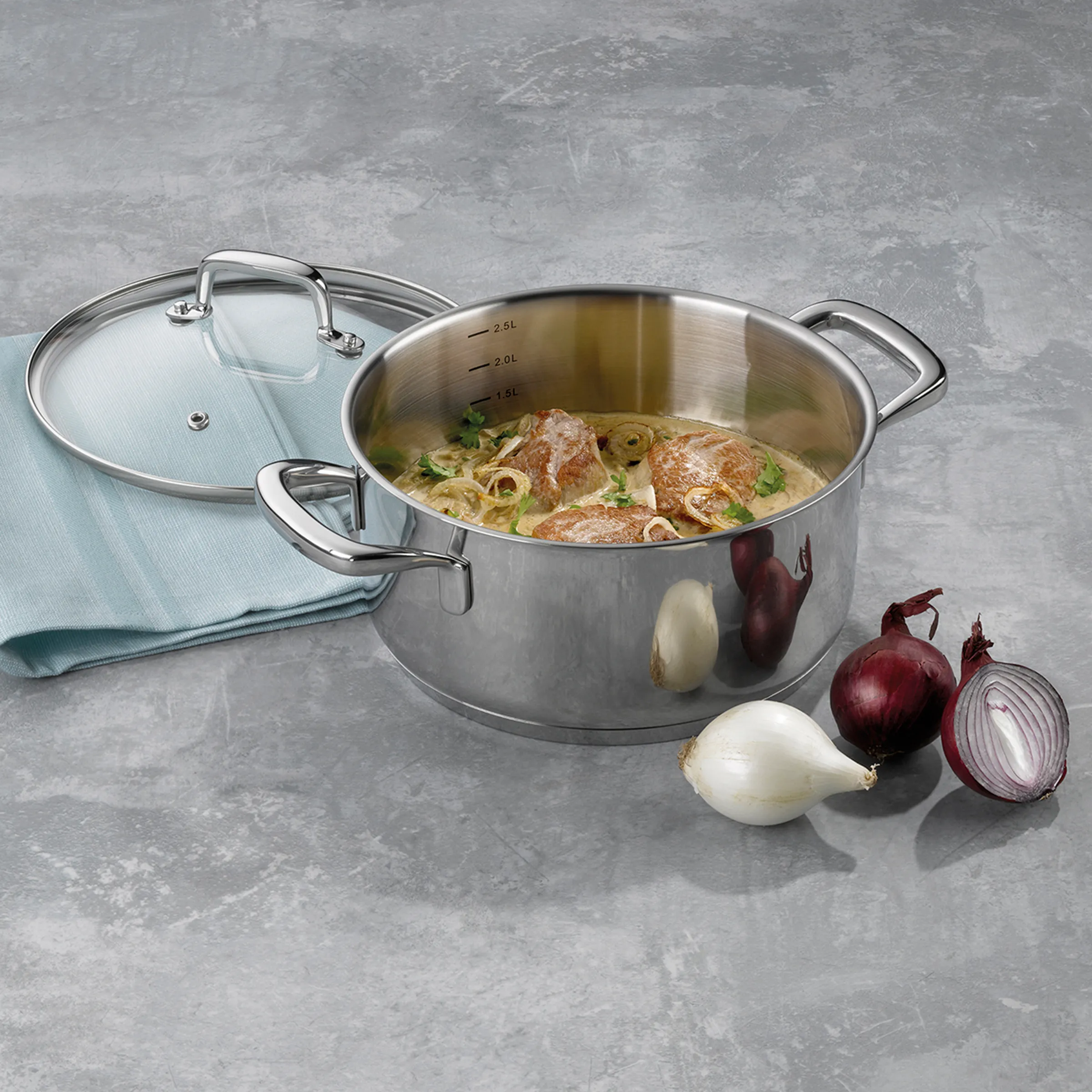 Edelstahl Kochtopf mit Nudelsuppe und Gemüse Edelstahltopf mit Deckel gefüllt mit Nudelsuppe, daneben rote und weiße Zwiebeln auf grauem Untergrund