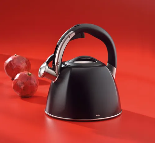 Flötenkessel Schwarz mit Edelstahlgriff - Eleganter Wasserkocher Teekocher Schwarzer Flötenkessel mit Edelstahlgriff auf rotem Hintergrund, dekoriert mit roten Granatäpfeln