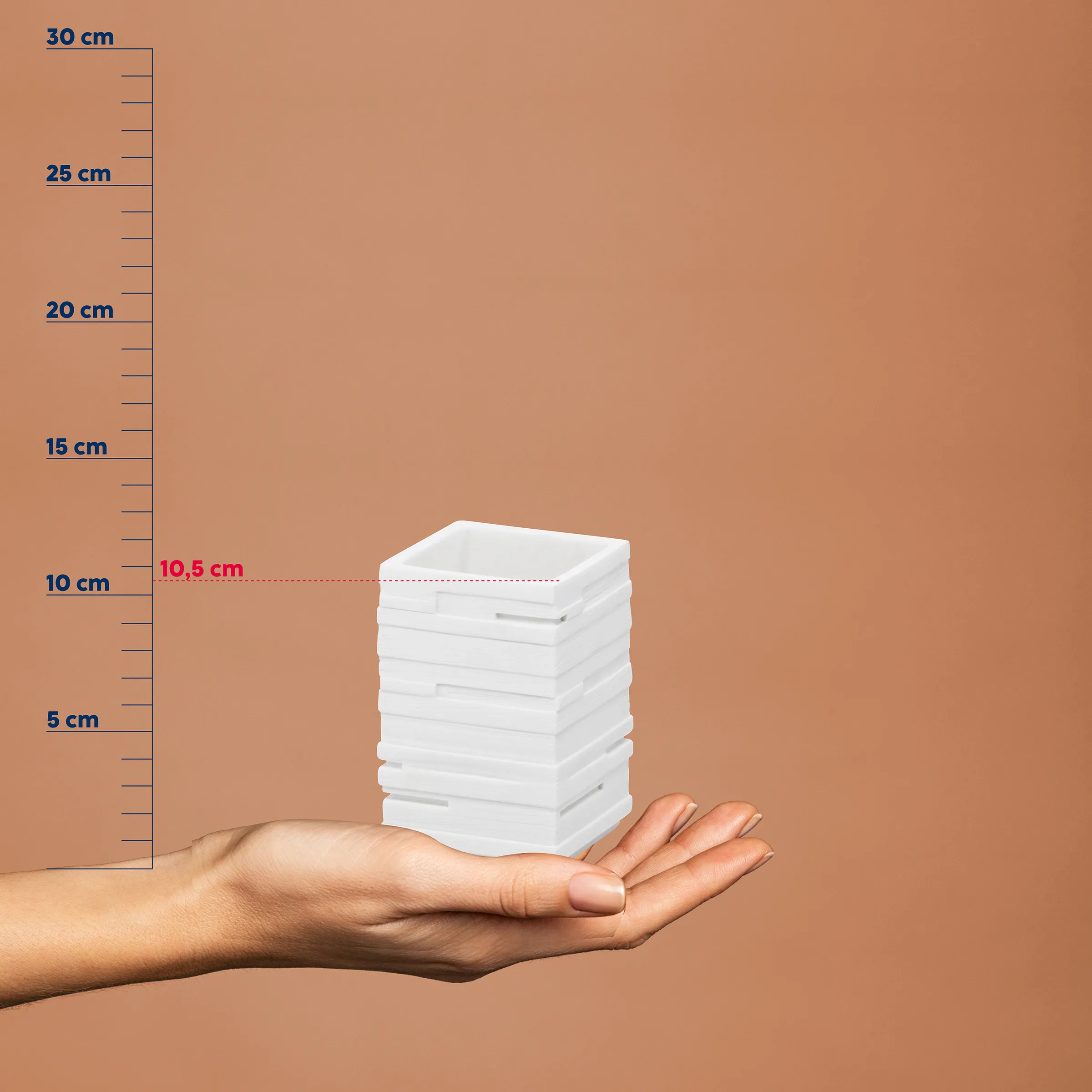 Produktgröße Vergleich: Kleine weiße Boxen mit Maßstab Hand hält einen Stapel weißer quadratischer Boxen neben einer Messskala, die eine Höhe von etwa 10,5 cm anzeigt.