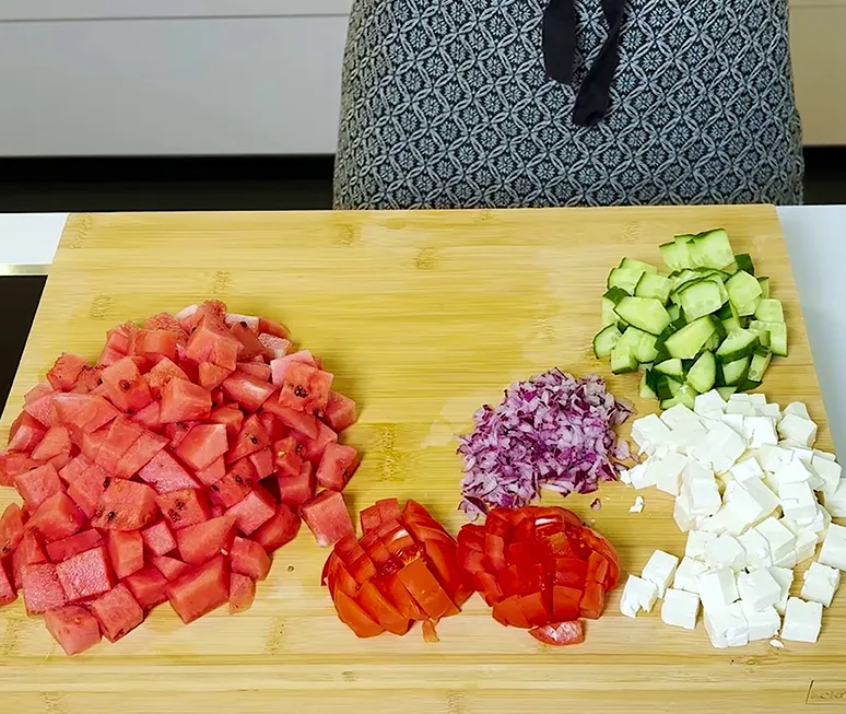 Frisches geschnittenes Gemüse und Feta auf Schneidebrett - Salat Zubereitung Geschnittenes Gemüse auf Bambus-Schneidebrett: Tomaten, Gurken, Paprika, rote Zwiebeln und Feta-Käse
