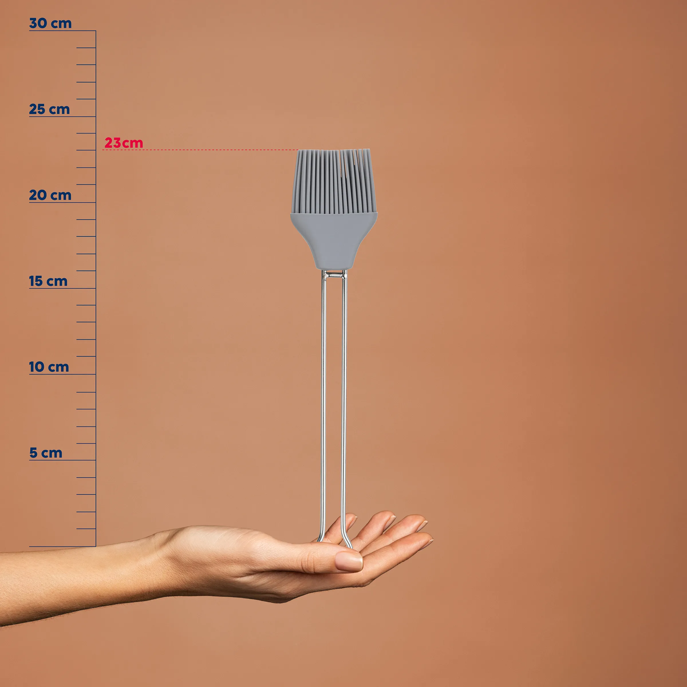 Silikon-Backpinsel 23cm - Küchenpinsel mit ergonomischem Griff Graue Silikon-Backpinsel mit Rillen auf Hand gehalten, Größenskala zeigt 23cm Höhe auf beigem Hintergrund