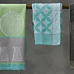 Türkis Handtuch und Wanddeko – Badezimmer Accessoires modern Türkisfarbenes Handtuch hängt neben dekorativem Wandbild an grauer Wand über dunklem Holzboden