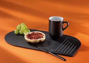 Servierboard schwarz mit Frühstück - Tartelette und Kaffeetasse Set Schwarzes Servierboard mit Tartelette, Deko und Kaffeetasse auf orangefarbenem Hintergrund