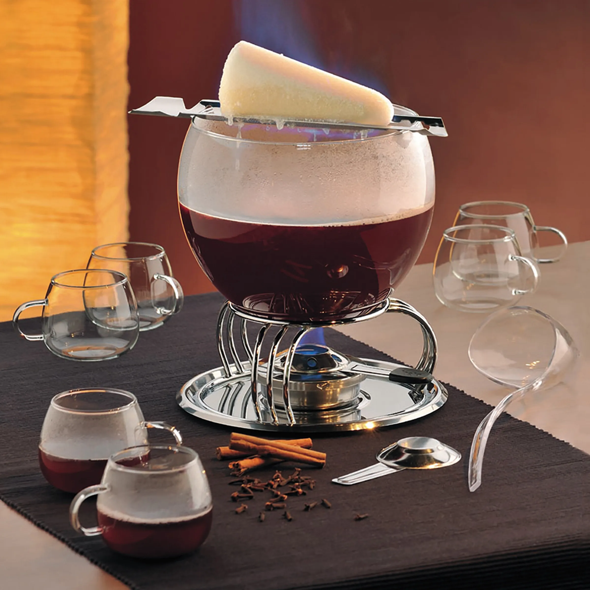 Glühwein Set mit Serviertopf und Gläsern Elegantes Glühwein-Set mit großem Topf, Schaumkrone, Zimtstangen, Nelken und mehreren Gläsern auf schwarzem Untergrund