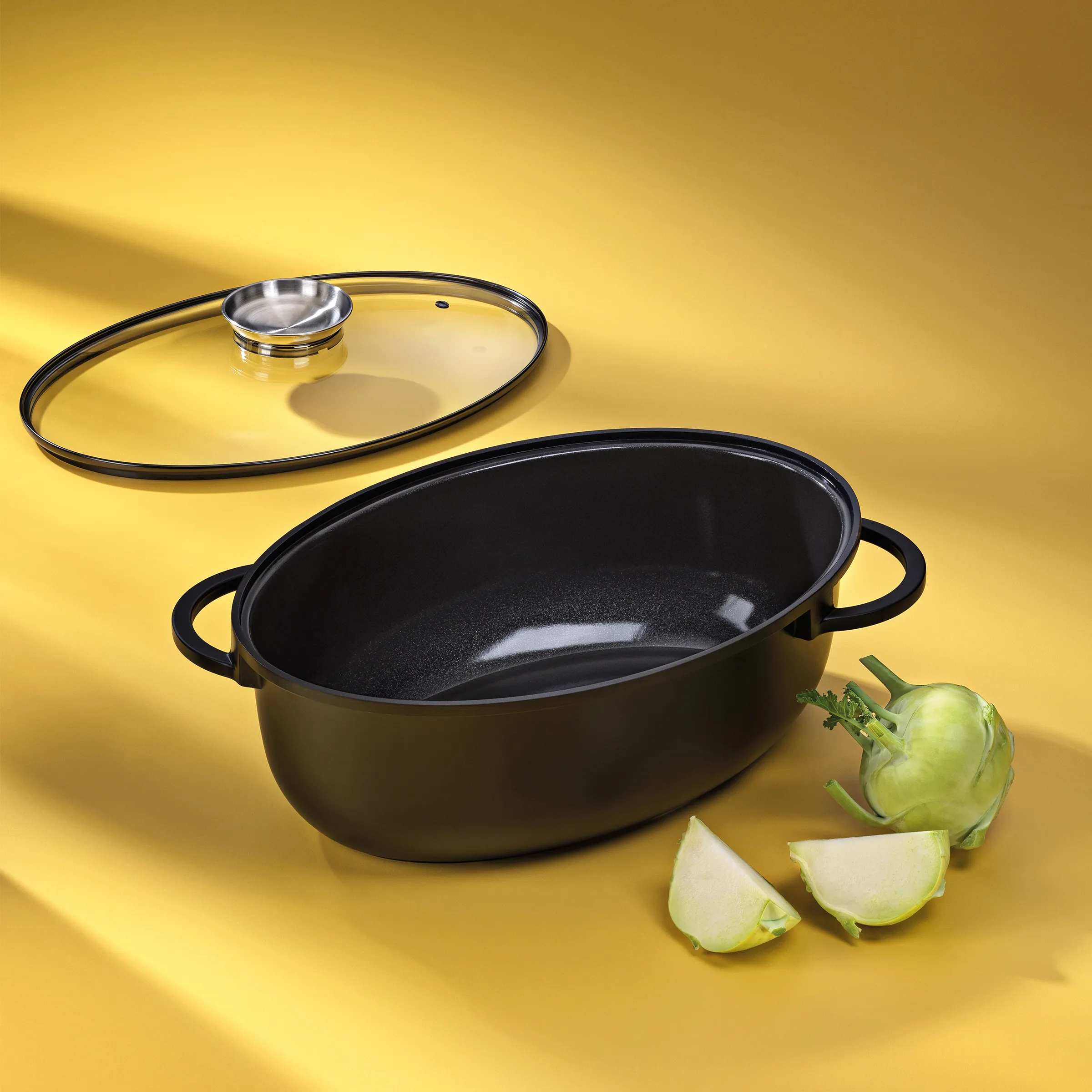 Kochtopf Set mit Glasdeckel und Auberginen Schwarzer Kochtopf mit Glasdeckel und grünen Auberginen auf gelbem Hintergrund