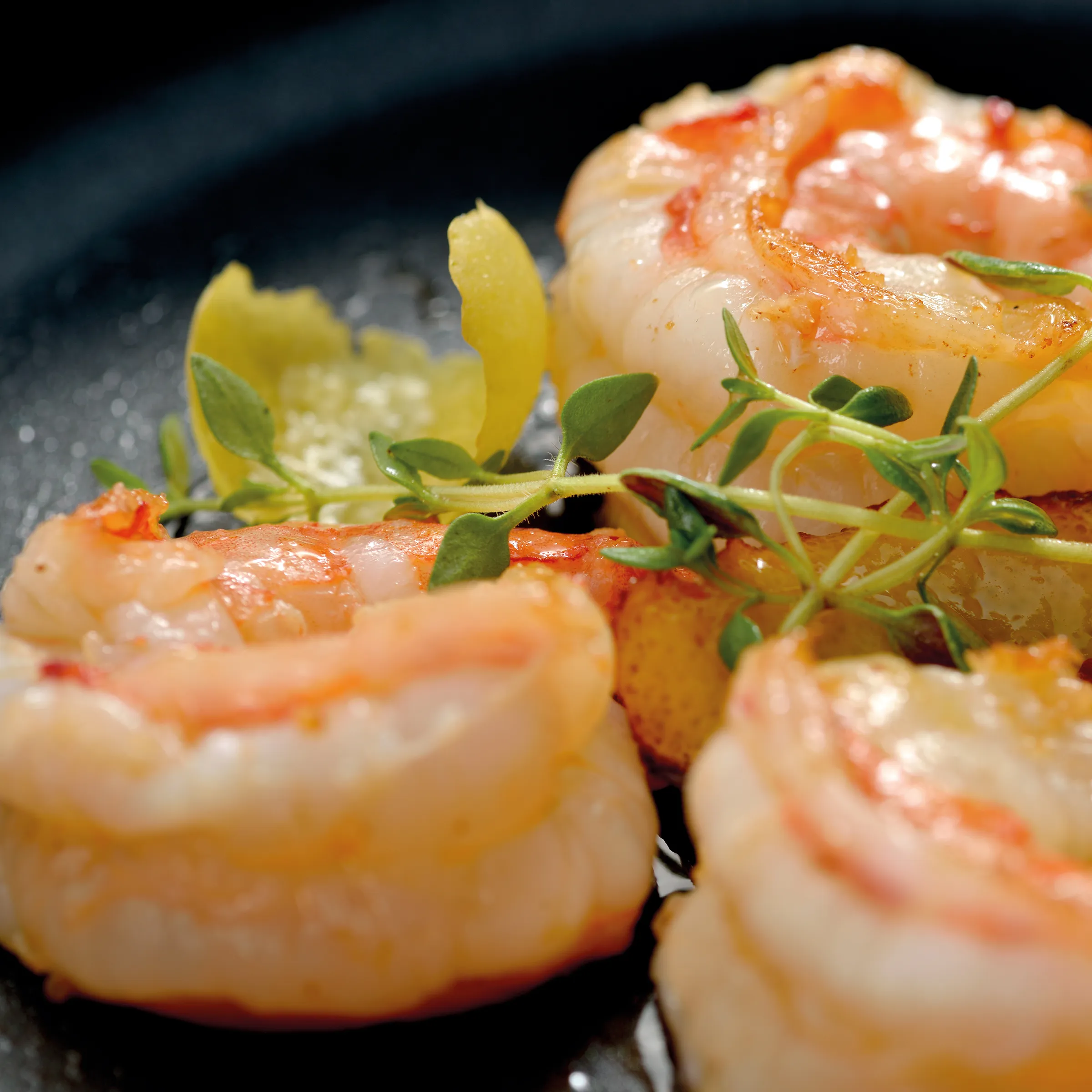 Gebratene Garnelen mit Kräutern und Zitrone - Gourmet Meeresfrüchte Gebratene Garnelen mit frischen Kräutern und Zitrone auf grauem Teller, appetitlich angerichtet