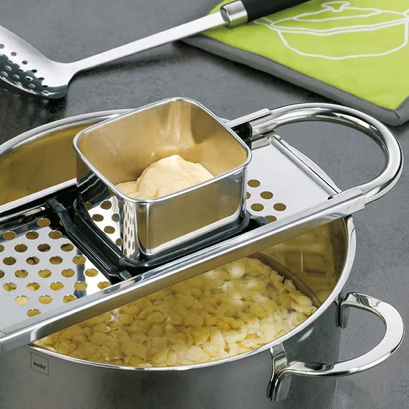 Edelstahl Dampfgarer-Set mit Einsätzen für Spätzle und Kartoffelpüree Mehrzweck-Dampfgarer aus Edelstahl mit Einsätzen, gefüllt mit Spätzle und Püree auf grauer Arbeitsfläche