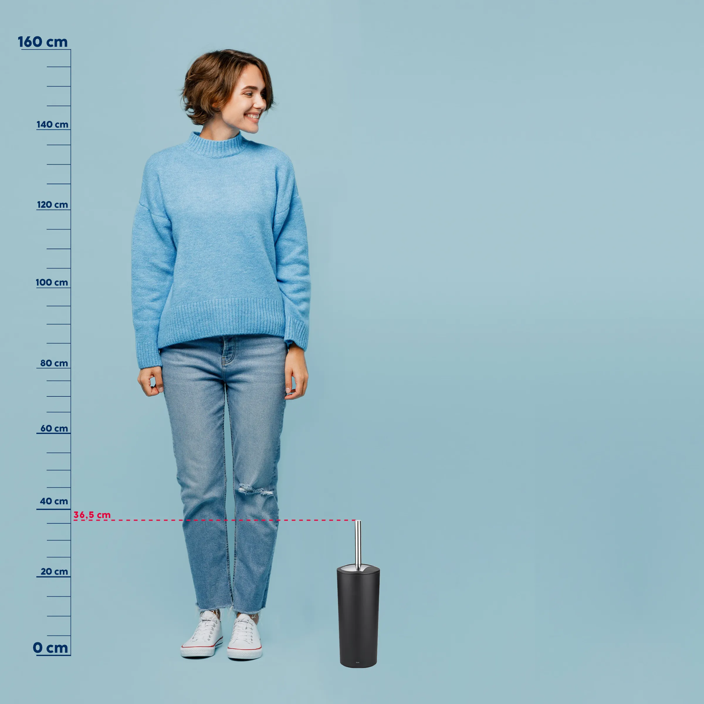 Frau in hellblauem Strickpullover und Jeans steht neben schwarzem Toilettenbürsten-Behälter mit Größenvergleich bei 36,5 cm