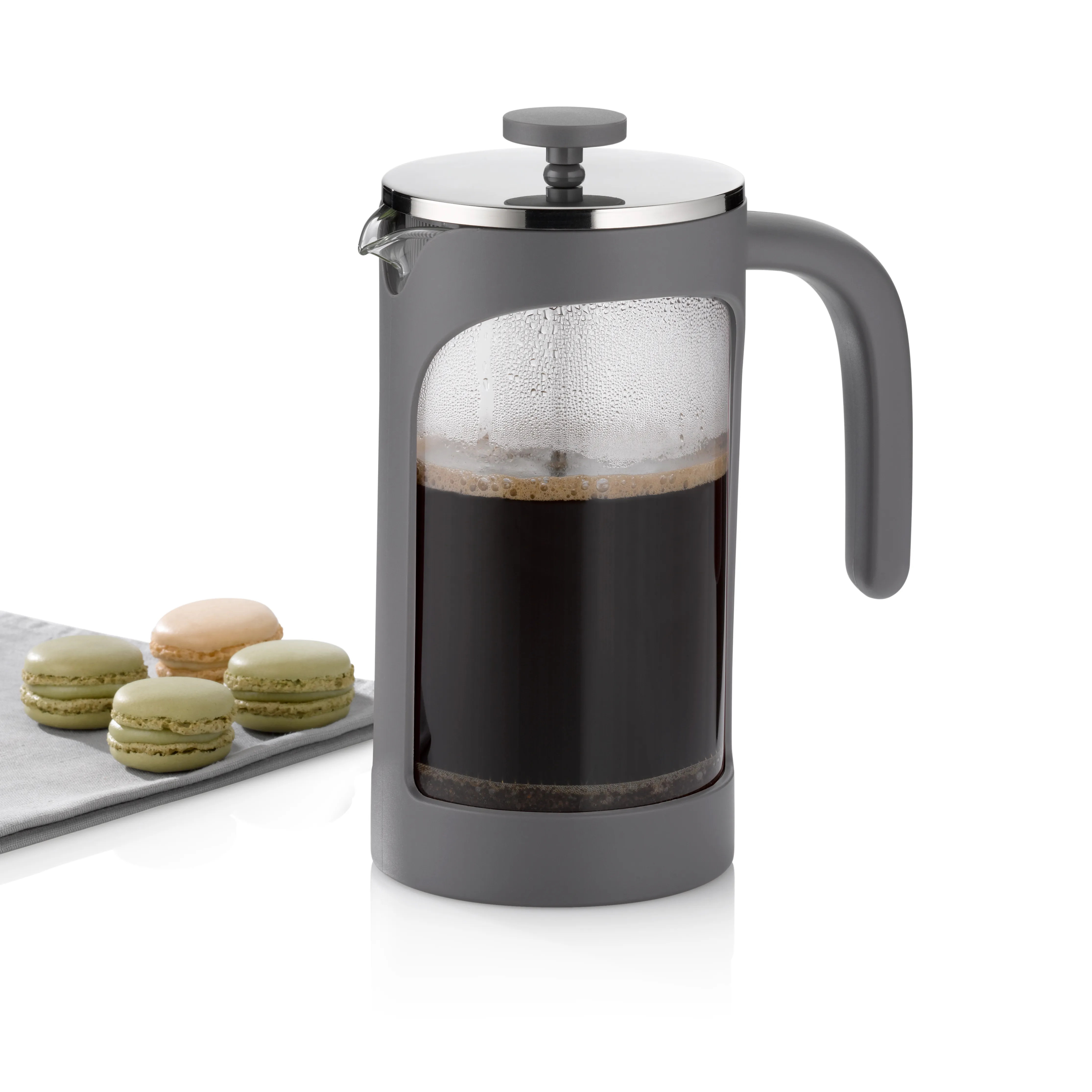 Pressekanneröhre Kaffeebrüher mit Kaffeebohnen Graue Pressekannenröhre mit schwarzem Kaffee und Crema, daneben Macarons auf Tablett