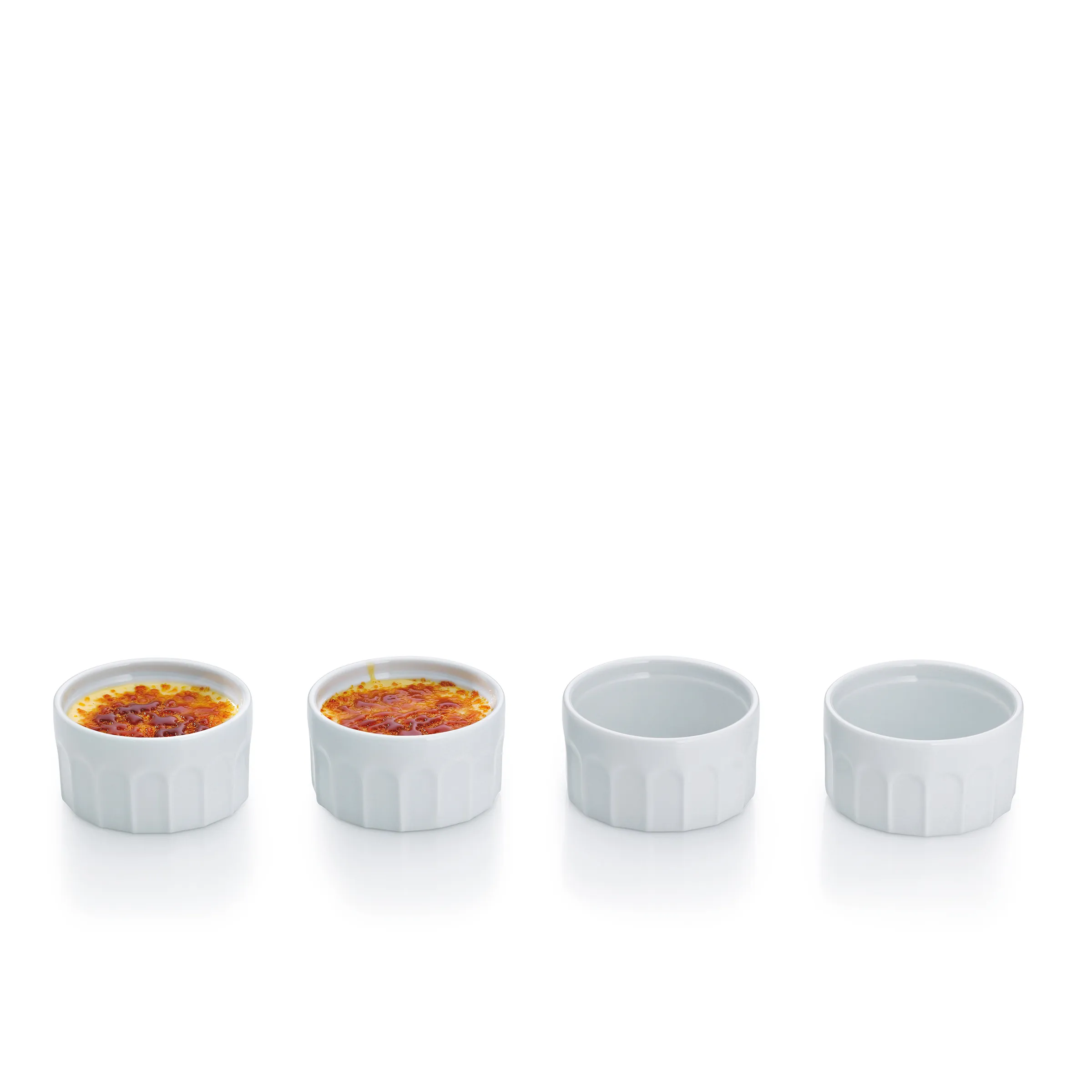 Crème brûlée in Keramikschüsseln - Klassisches Dessert Vier weiße Keramikschüsseln nebeneinander, zwei mit Crème brûlée mit karamelisierter Oberfläche, zwei leer