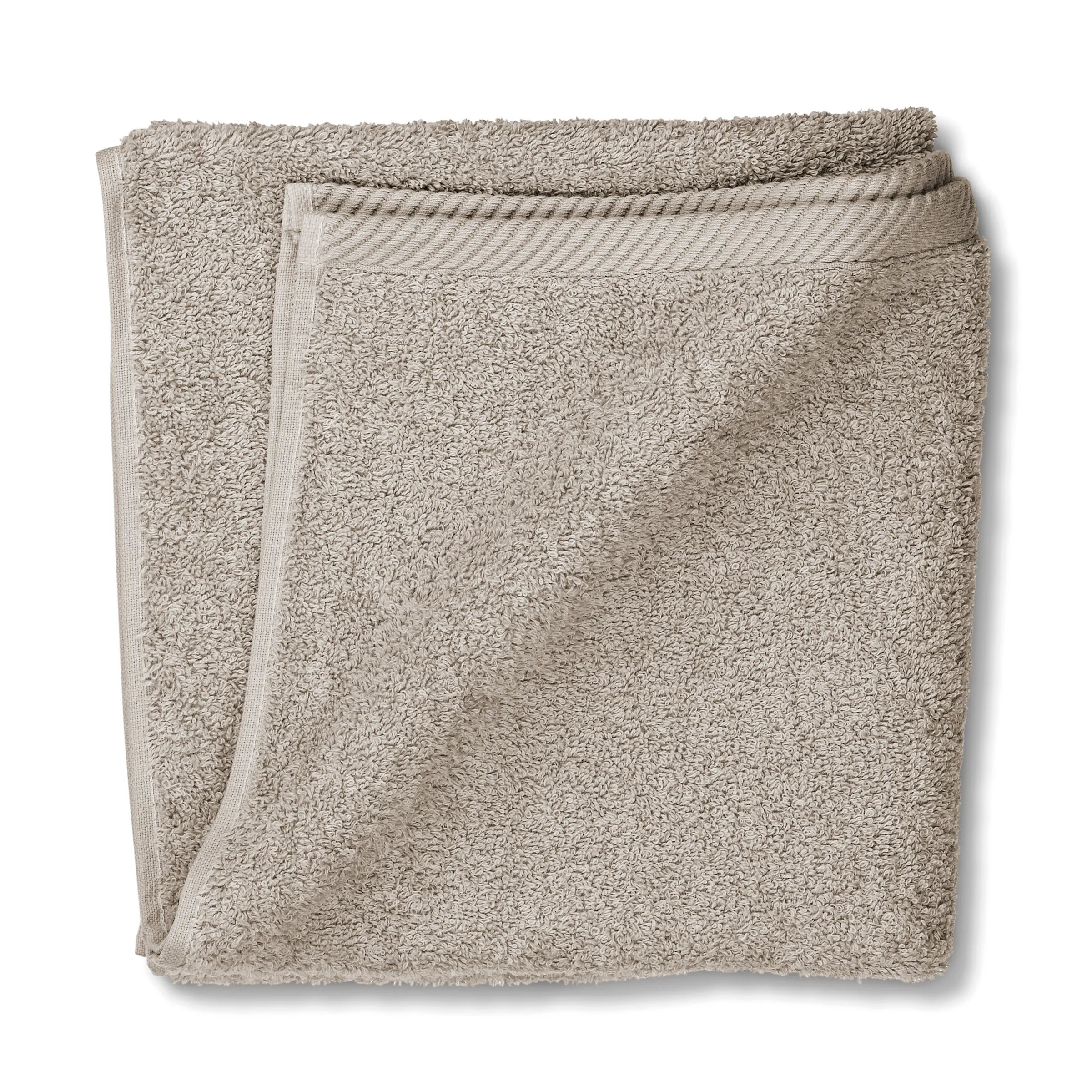 Beige Baumwoll-Handtuch gefaltet - Badtextilien Beigefarbenes Handtuch aus Baumwolle, gefaltet auf weißem Hintergrund mit sichtbarer Textur