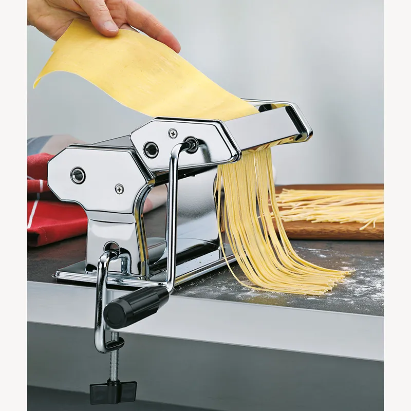 Nudelmaschine Edelstahl - Frische Pasta selbst machen Edelstahl-Nudelmaschine mit Handkurbel produziert frische Pasta-Fäden auf Arbeitsplatte