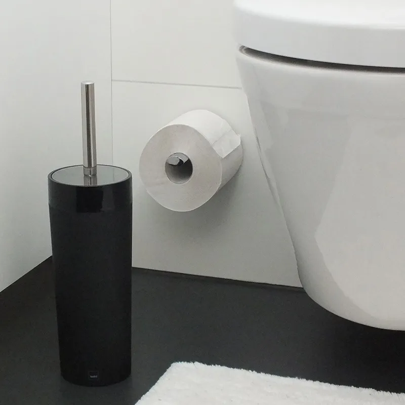 Badezimmer Accessoires Set - Toilettenbürste und Papierhalter Modernes Badezimmer mit schwarzer Toilettenbürste, Toilettenpapierhalter und weißem Porzellan-Spülklo an grauer Wand
