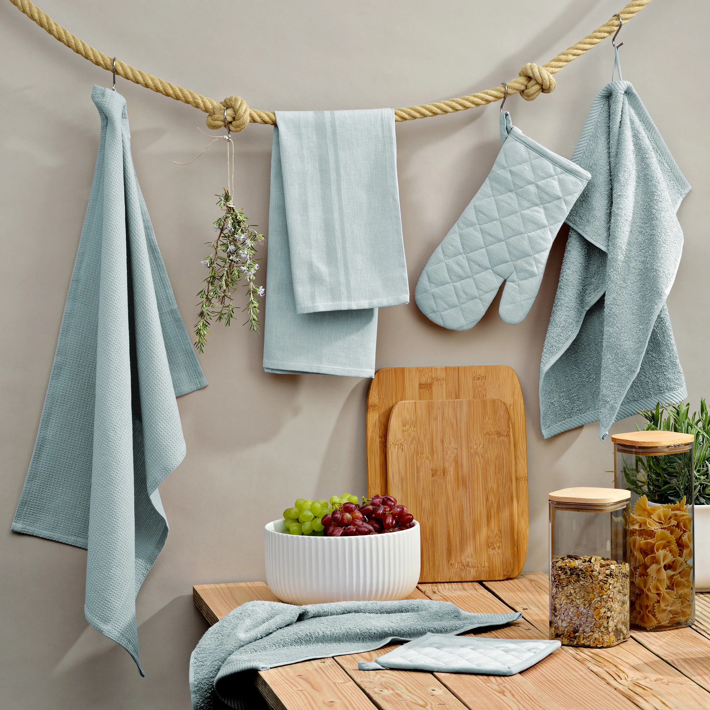 Küchenhandtücher und Küchenausstattung Set Küchenausstattung mit grünen und grauen Textilien, Schneidebrettern aus Holz, Obstschale mit Trauben und Aufbewahrungsbehältern