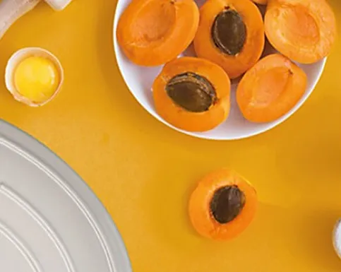Fresh Apricots - Buy Organic Fruits Online Fresh apricots halved on white plate with juice against yellow background and tableware