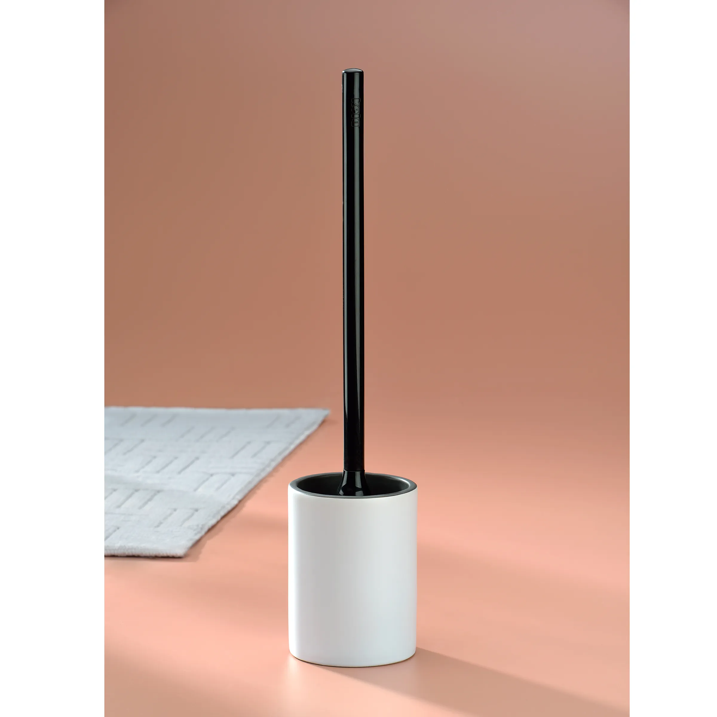 Toilettenbürste weiß mit Behälter - modern & praktisch Weiße Toilettenbürste mit schwarzem Griff und Behälter auf rosa Hintergrund neben weißem Handtuch