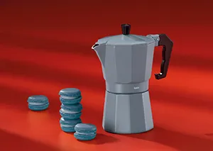 Espressokanne Aluminium mit Kaffeekapseln – Italian Moka Pot Graue Espressokanne aus Aluminium mit schwarzem Griff auf rotem Hintergrund, daneben blaue Kaffeekapseln