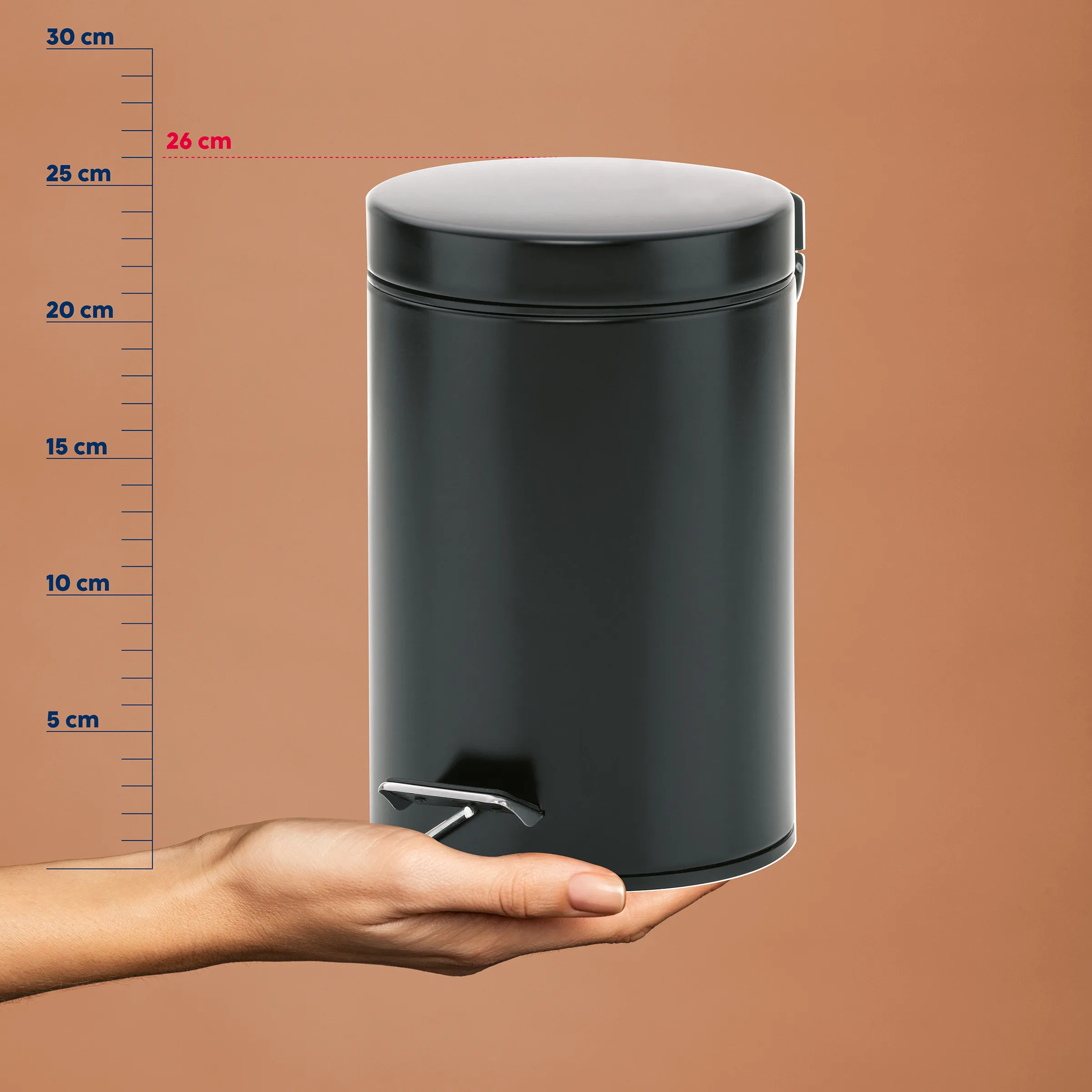 Treteimer schwarz 12 Liter Kosmetikeimer Schwarzer Treteimer mit weißem Deckel auf einer Hand, daneben eine Messskala von 0-30 cm. Der Eimer ist etwa 26 cm breit.
