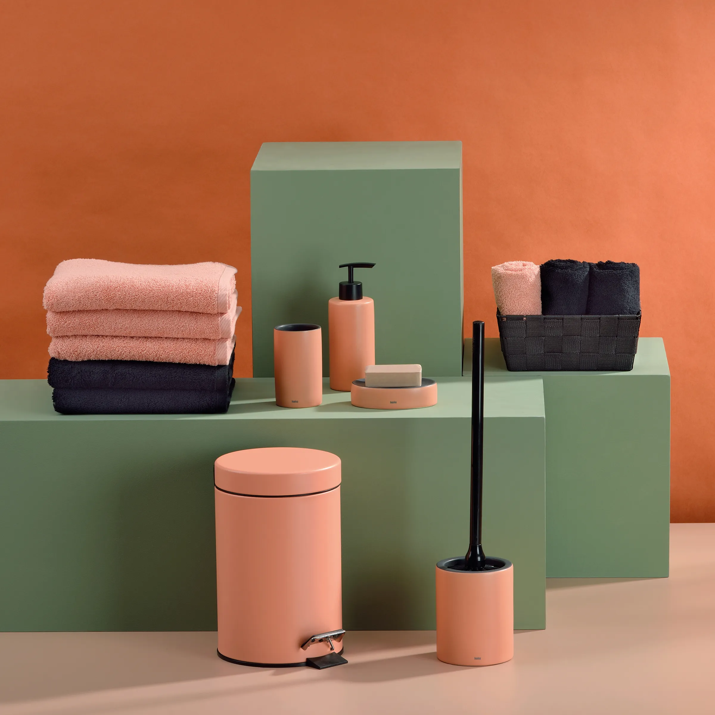 Badezimmer Accessoires Set - moderne Badausstattung Badezimmer-Set mit rosa und schwarzen Handtüchern, Seifenspendern, Zahnbürstenhalter und Behältern auf grünen Podesten.