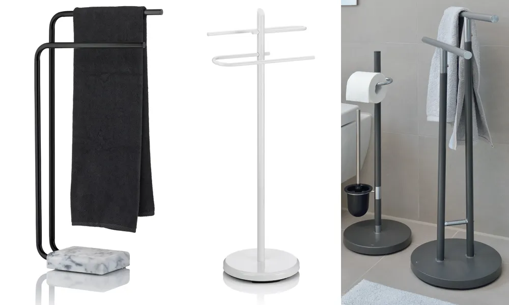 Badezimmerständer und Handtuchhalter für modernes Badezimmer Drei verschiedene Badezimmerständer: schwarzer Handtuchständer, weißer Doppelarm-Ständer und grauer Kombination-Ständer mit Toilettenpapierhalter und Handtuchhalter.