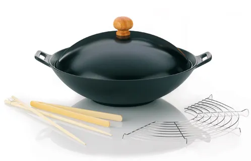 Wok Set mit Deckel und Kochbesteck Schwarzer Wok mit Holzdeckel und Metallgriffen, daneben Bambusbesteck und Metall-Kochutensilien auf weißem Hintergrund
