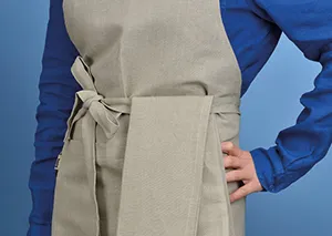 Beige Schürze mit Tasche und Bindebändern - Koch- und Arbeitsschürze Beige Schürze mit Seitentasche und Bindebändern getragen über blauem Hemd