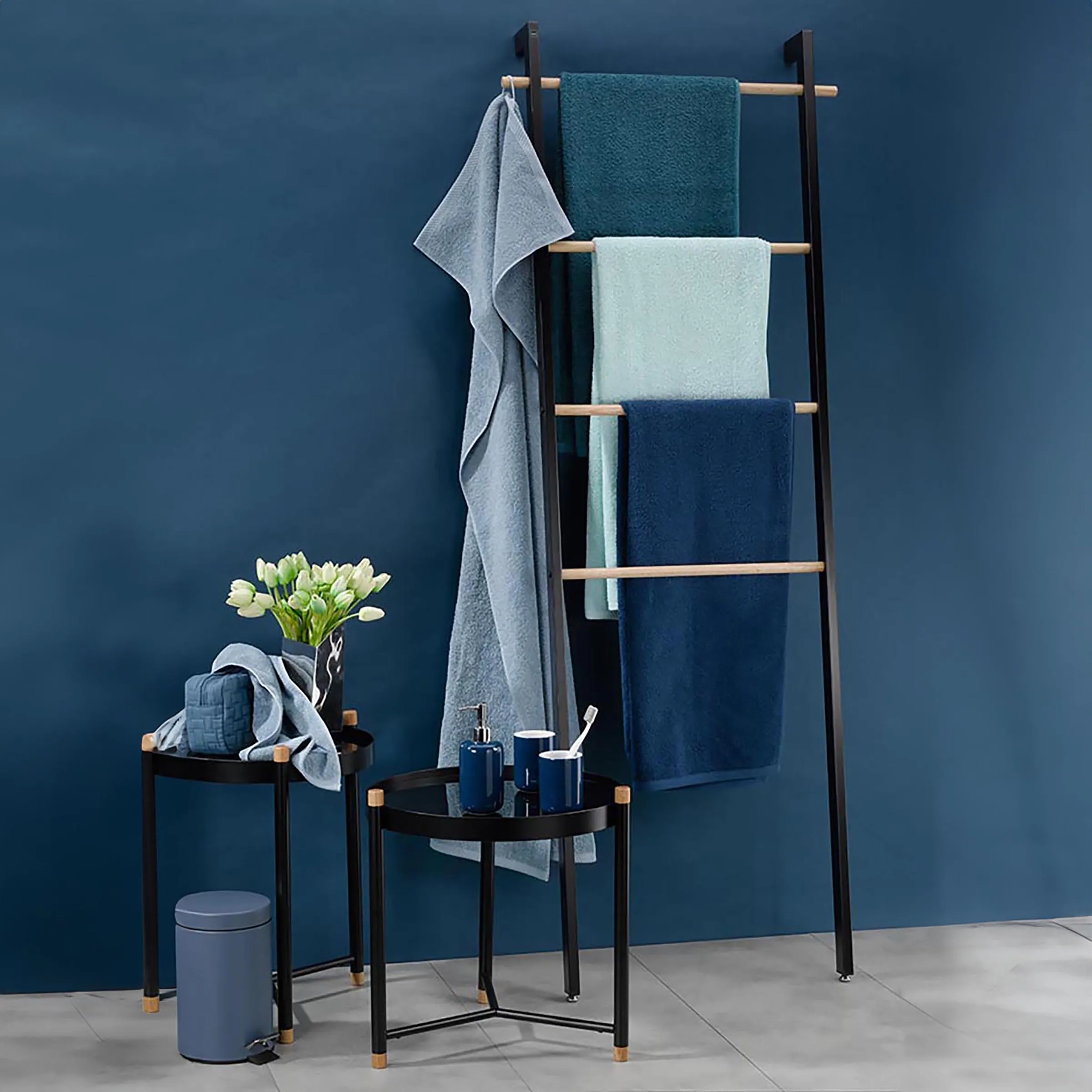 Handtuchleiter Badezimmer - Moderne Handtuchhalter Leiter mit blauen Handtüchern Handtuchleiter aus schwarzem Metall mit Holzsprossen, dekoriert mit blauen Handtüchern vor blauer Wand