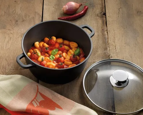 Gemüseeintopf Rezept: Bunter Topf mit Paprika und Gemüse Schwarzer Topf mit Gemüseeintopf auf Holztisch, daneben Glasdeckel und rote Chili