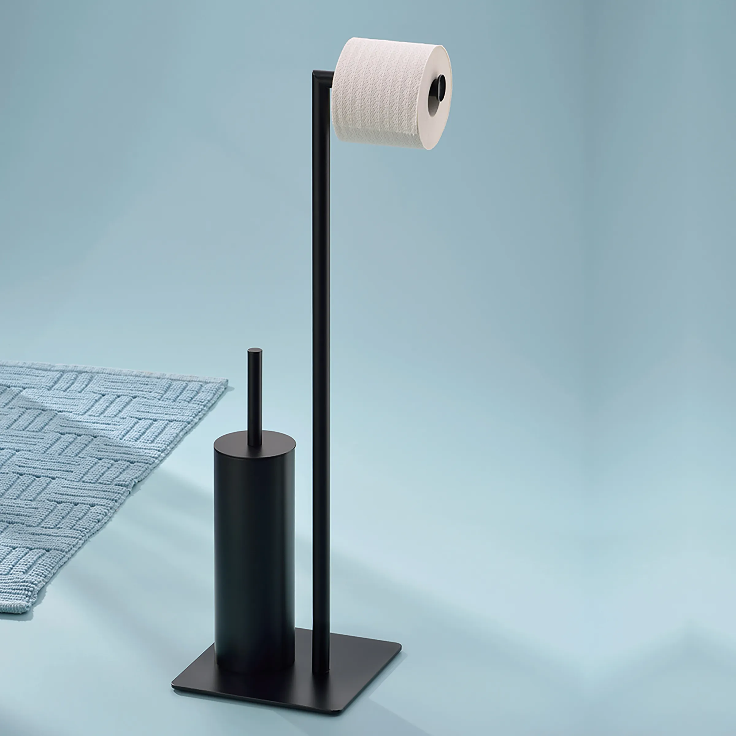 WC-Garnitur Stand Schwarz - Toilettenpapierhalter mit WC-Bürste Schwarzer WC-Garnitur-Stand mit Toilettenpapierhalter und WC-Bürste auf blauem Hintergrund