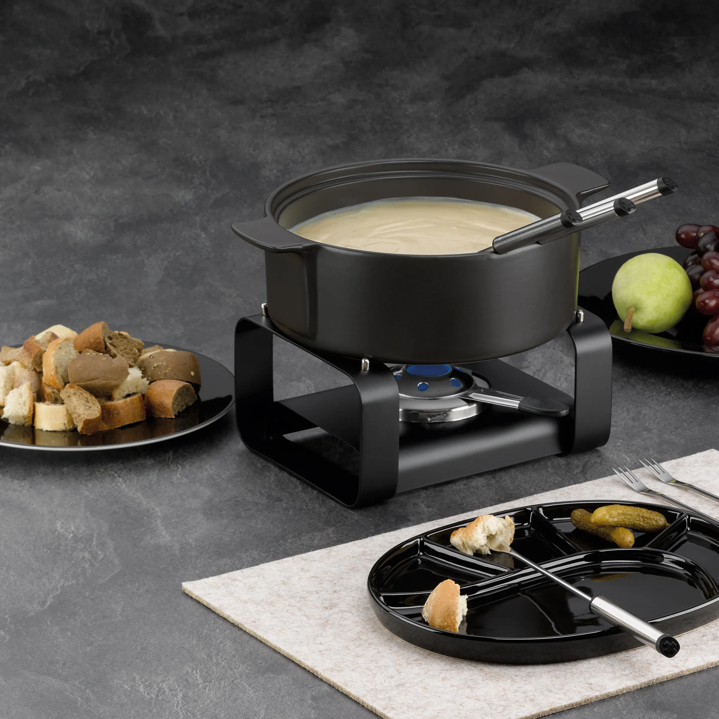 Käse Fondue Set - Klassisches Fondue Raclette Geschirr Schwarzes Fondue-Set mit Käsefondue-Topf auf Ständer, Bread und Obst auf grauem Hintergrund
