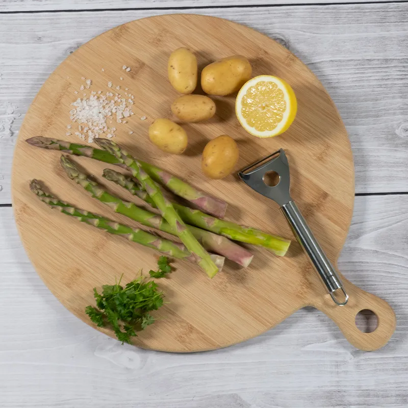 Spargel zubereiten: Frische Zutaten auf Schneidebrett Holzschneidebrett mit frischen Zutaten: Spargel, Kartoffeln, Zitrone, Petersilie, Salz und Spargelschäler