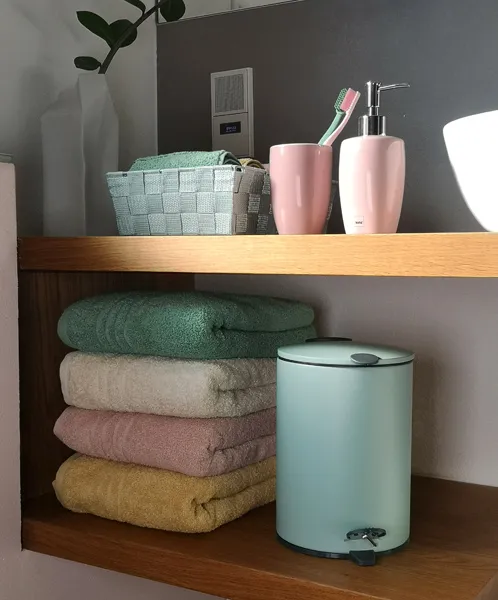 Badezimmerregal mit Handtüchern, rosa Zahnbürstenhalter, Seifenspender und Mülleimer aus Holz und Metall