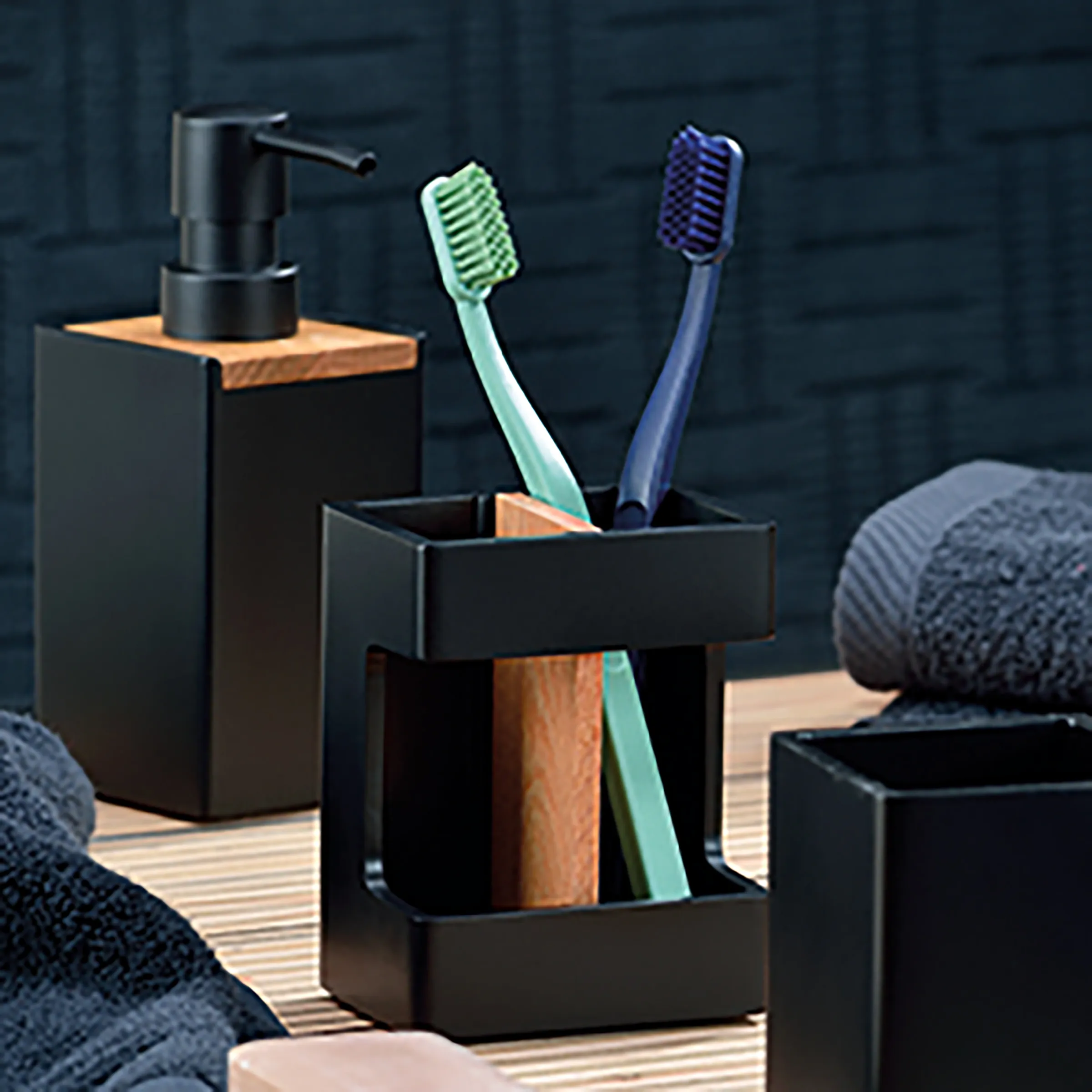 Schwarzes Badezimmer-Set mit Seifenspender, Zahnbürstenhalter mit grüner und blauer Zahnbürste auf Holzplattform