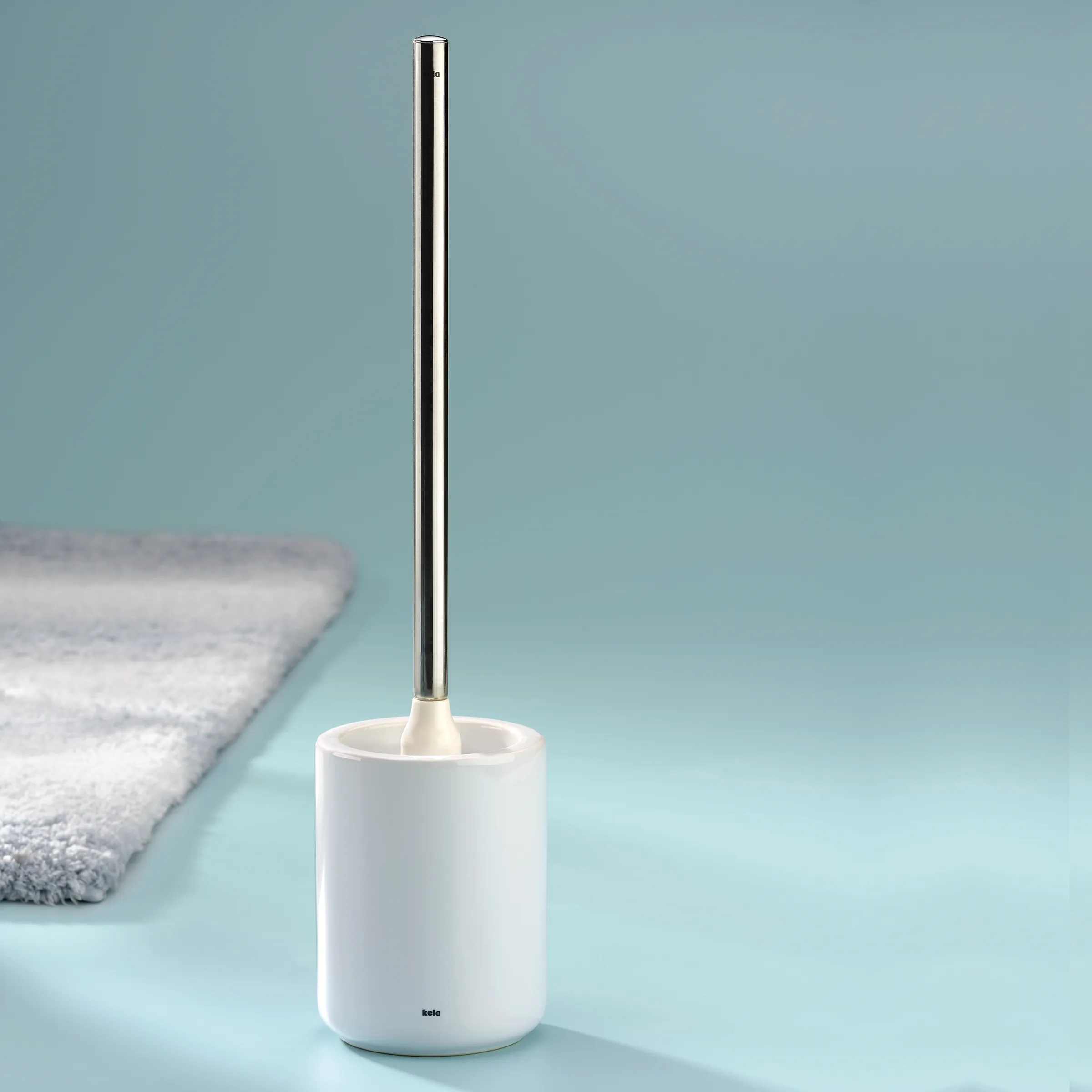 Toilettenbürste Keramik mit Edelstahlgriff - modernes Badezimmer Design Weiße Toilettenbürste mit Keramikbürste und Edelstahlgriff neben grauem Handtuch auf hellblauem Hintergrund