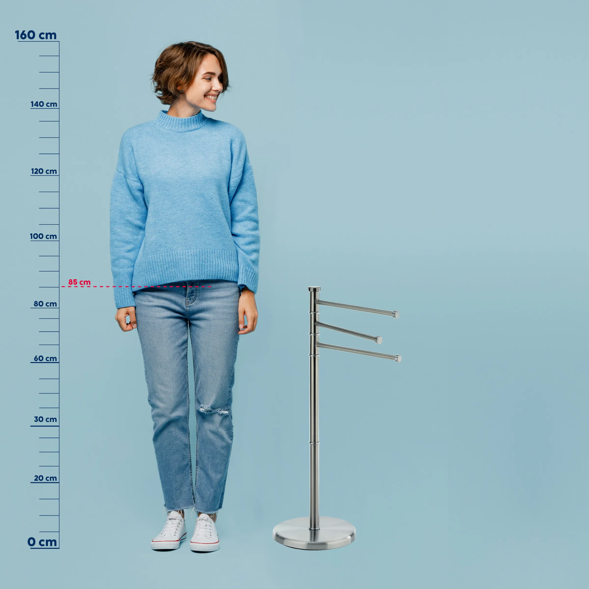 Kleiderständer Größenvergleich - tragbar mit Größenskala Frau in hellblauem Strickpullover und Jeans steht neben einem Kleiderständer mit drei horizontalen Stangen zur Größenvergleich-Messung.