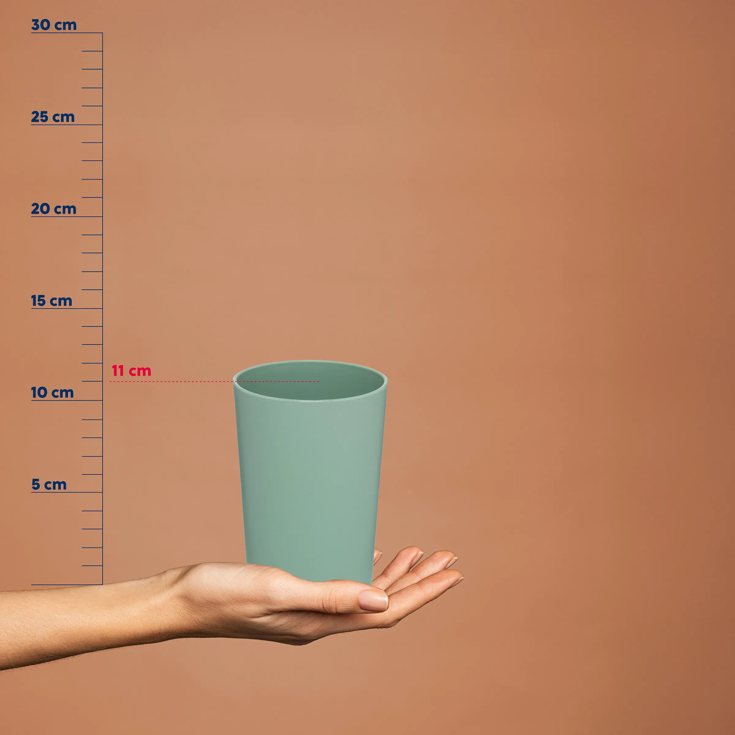 Trinkbecher Größe Maße Durchmesser Türkisfarbener Trinkbecher mit Größenangabe von 11 cm Durchmesser, in einer Hand gehalten vor Messskala